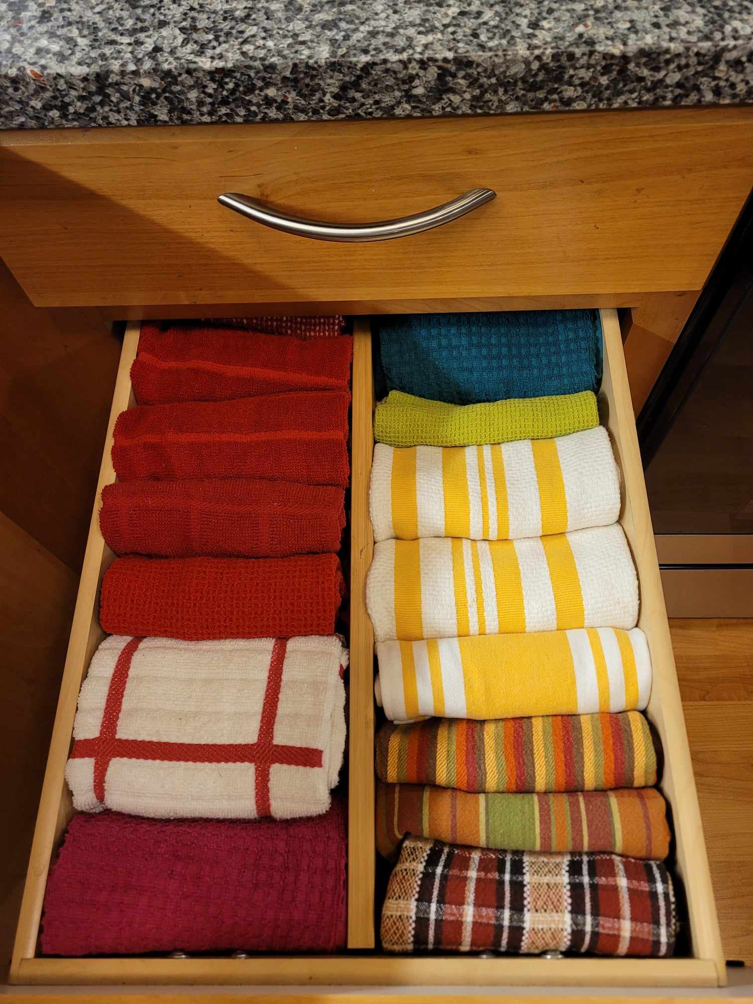 After organization image of kitchen towel drawer with towels file folded and divided with a bamboo drawer divider