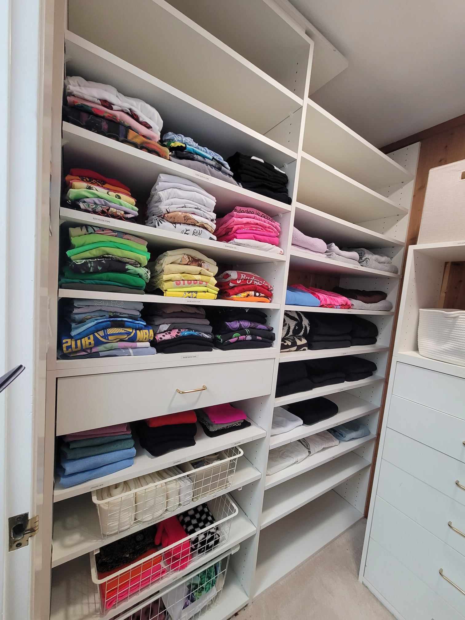 Primary closet organization with everything neatly folded and color-coded