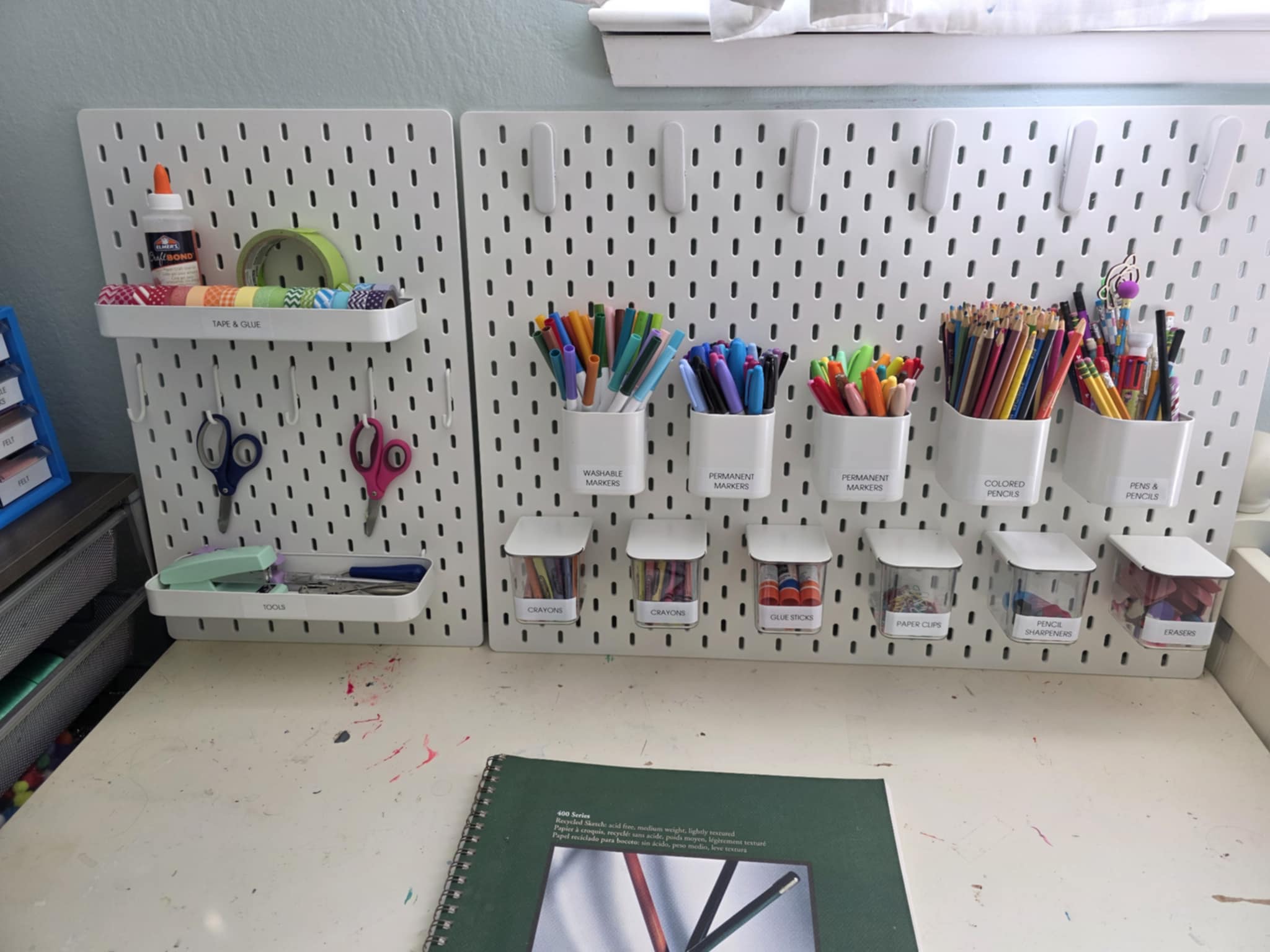 IKEA pegboard with craft supplies organized in cups and trays