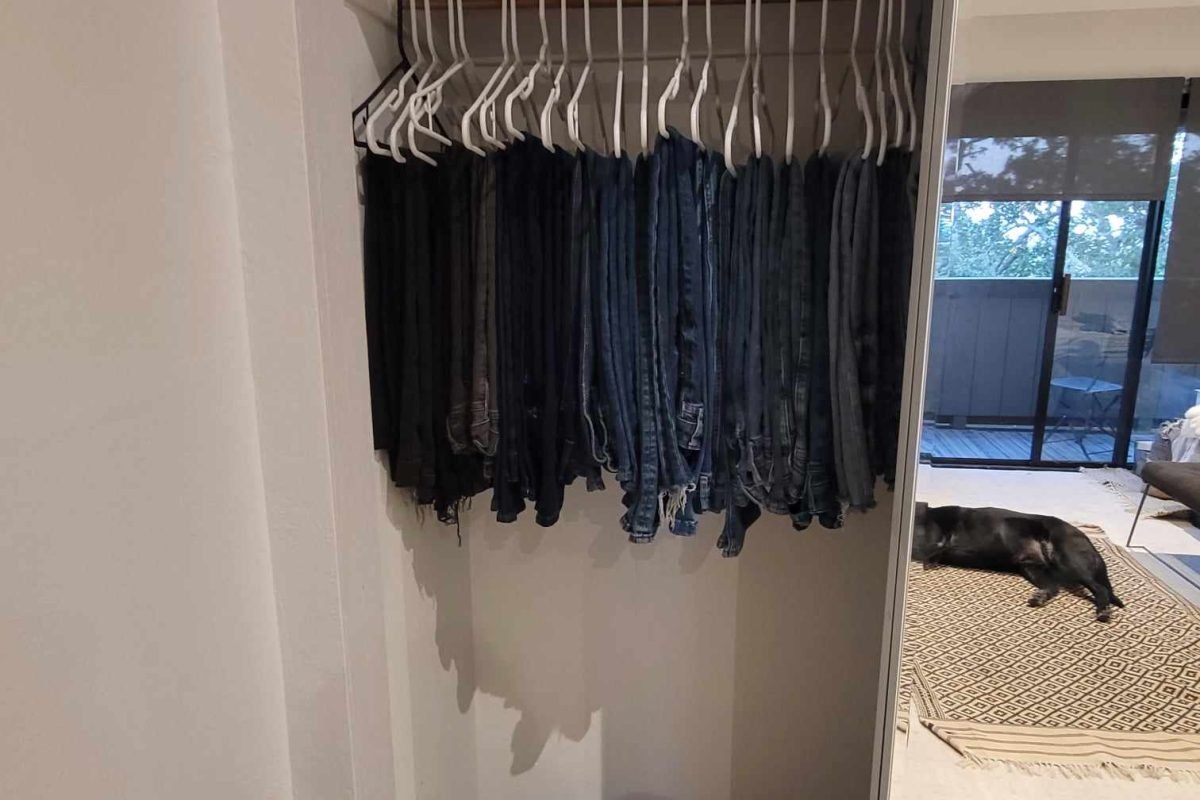 Sweaters neatly folded and jeans neatly hung with shoes organized on the floor of a primary closet